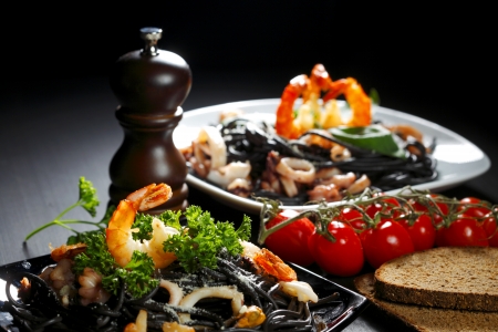 Black spaghetti with seafood on black tableの写真素材