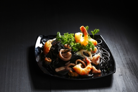 Black spaghetti with seafood on black tableの写真素材
