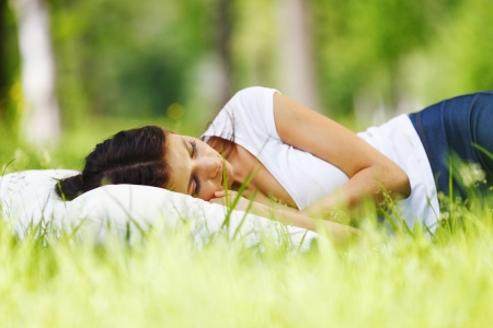 Young woman sleeping on soft pillow in fresh spring grassの写真素材