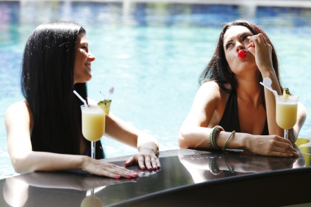 Two beautiful women relaxing in swimming pool with cocktailsの写真素材