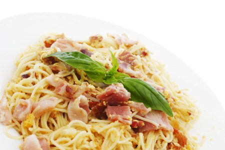 Spaghetti carbonara with fried bacon and basil isolated on whiteの写真素材