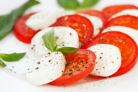 Tomato and mozzarella with basil leaves on a plateの写真素材