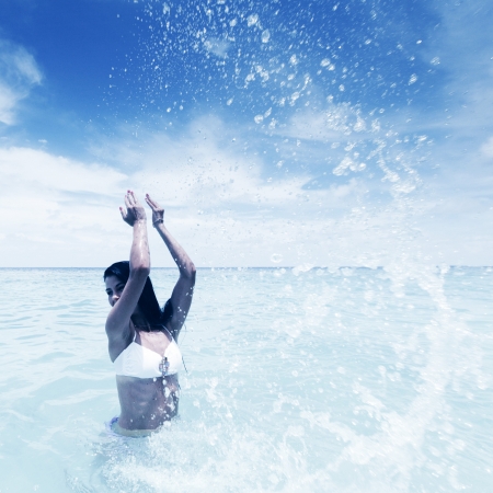 Cheerful pretty young woman splashin in seaの写真素材