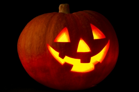 Illuminated cute halloween pumpkin on black の写真素材