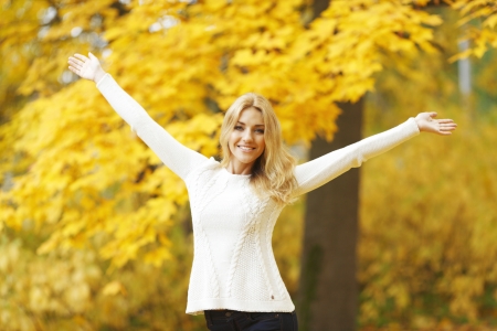 Happy woman with raised hands in autumn parkの写真素材
