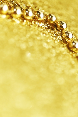 Golden christmas decoration beads on shiny glitter backgroundの写真素材
