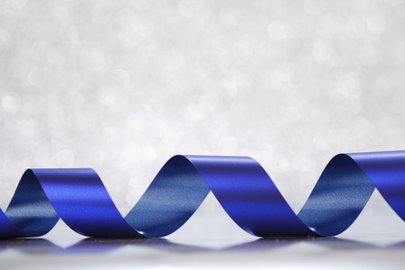 Card with blue gift bow on shiny silver backgroundの写真素材