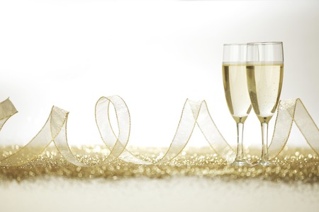 Two champagne flutes and decoration on gold shiny backgroundの写真素材