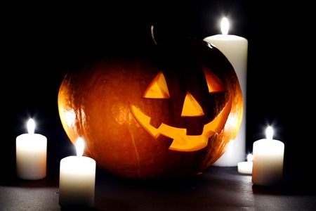 Halloween pumpkin surrounded with candles isolated on black backgroundの写真素材