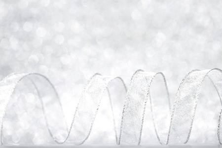 Curly silver serpentine on shiny glitter background, holiday conceptの写真素材