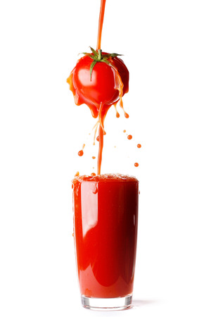 Juice pouring from tomato into glass isolated on white backgroundの写真素材