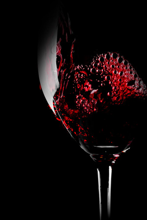 Glass of red wine close-up isolated on black backgroundの写真素材