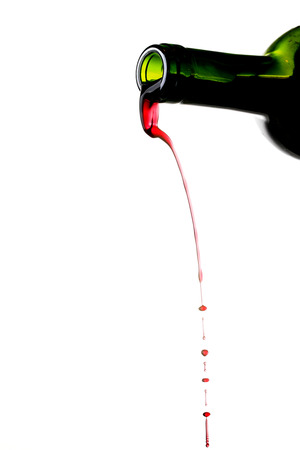 Red wine pouring from bottle isolated on white backgroundの写真素材