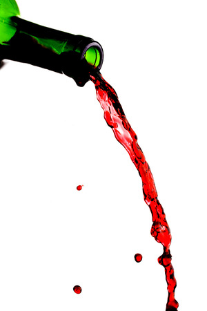 Red wine pouring from bottle isolated on white backgroundの写真素材