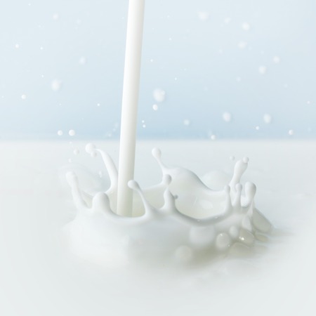 Pouring milk splash on blue background close-up