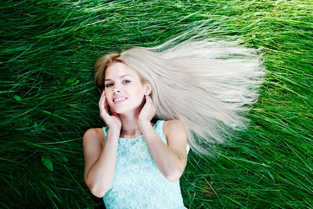 beautiful young woman in blue dress lying on grassの写真素材