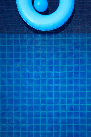 Swim ring and toy ball floating in a blue swimming pool