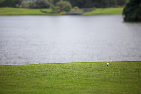 Golf ball on course with pond on backgroundの写真素材