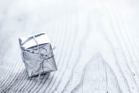 One small silver gift box on wooden background macroの写真素材