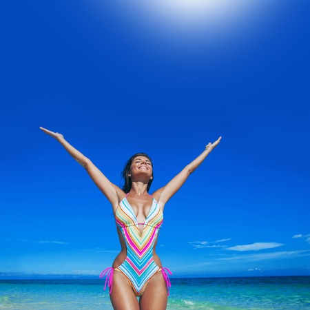 Beautiful happy woman with raised hands on beachの写真素材