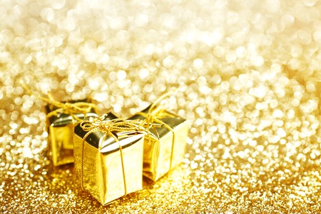 Gold decorative boxes with holiday gifts on abstract gold backgroundの写真素材