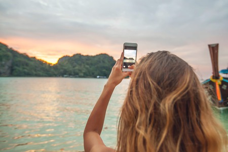 Woman taking photos with smartphone in Thailandの写真素材