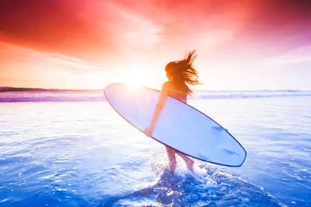 Beautiful sexy surfer girl on the beach at sunsetの写真素材