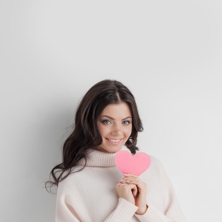 Beautiful woman holding Valentines day paper heart cardの写真素材