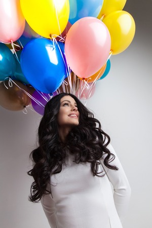 Cheerful woman holding many colorful balloons, celebration and happiness conceptの写真素材