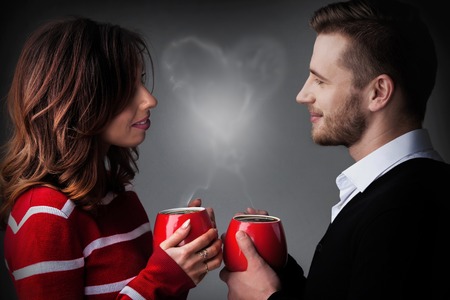 Young couple holding coffee mags with heart shaped steam, Valentine's day conceptの写真素材