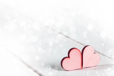 Two wooden red painted Valentine day hearts on white wooden backgroundの写真素材