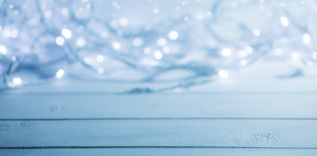 Glowing garland defocused bokeh lights on wooden backgroundの写真素材