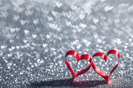 Two ribbon hearts on glowing bokeh lights backgroundの写真素材