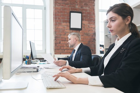 Business people working with computers in office sitting in a row