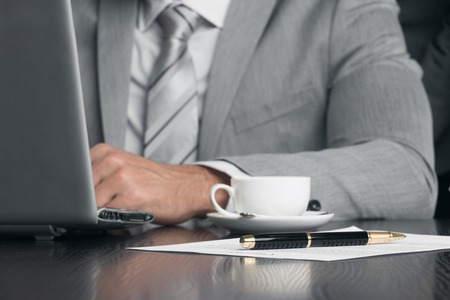 Close up of business man working with documents and laptop in officeの写真素材