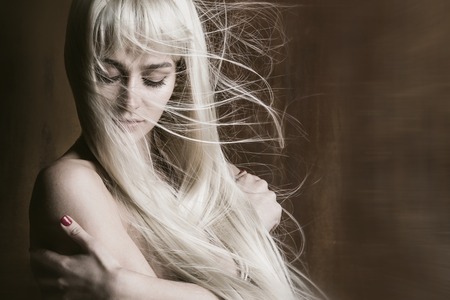 Studio portrait of beautiful sexy woman with long blonde flying hairの写真素材
