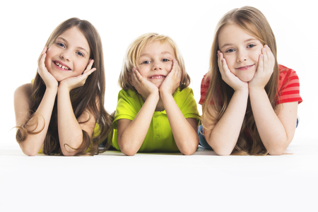 Three happy children laying down, isolated on white backgroundの写真素材