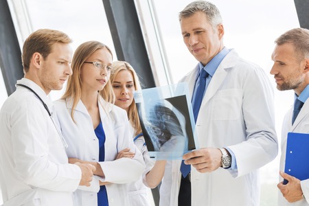 Group of doctors look and discuss x-ray in a clinic or hospitalの写真素材