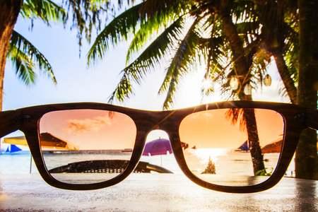 View on tropical beach with palm trees through sunglassesの写真素材