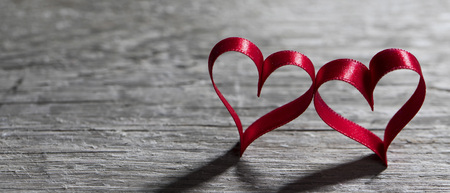 Two red ribbon hearts on wooden backround, Valentine day conceptの写真素材