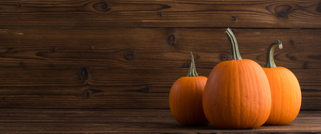 Three orange pumpkins on dark wooden background, Halloween conceptの写真素材