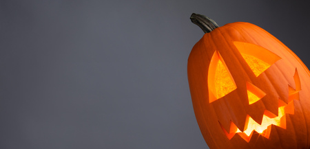 Funny glowing Halloween Pumpkin on gray backgroundの写真素材