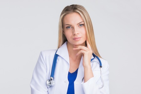 Close-up portrait of a beautiful thoughtful female doctor on gray backgroundの写真素材