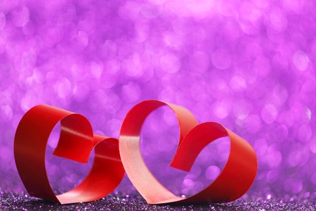 Decorative hearts of red ribbon on shiny glitter backgroundの写真素材