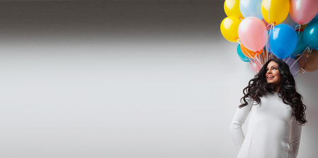 Beautiful young woman with many colorful balloons, copy space for textの写真素材