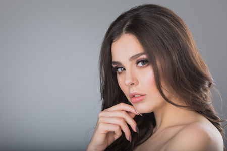 Portrait of beautiful brunette woman holding hand on chinの写真素材
