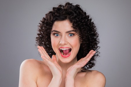 Surprised excited beautiful woman screaming amazed in joy, gray backgroundの写真素材