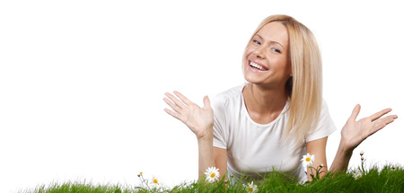 Beautiful young blonde woman lying on grass with chamomile flowers, isolated on white backgroundの写真素材