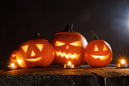 Halloween pumpkin head jack lantern and candles on wooden backgroundの写真素材