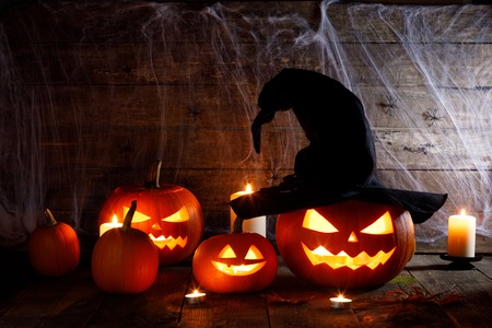 Jack O Lantern Halloween pumpkin with witches hat, spiders on web and burning candlesの写真素材